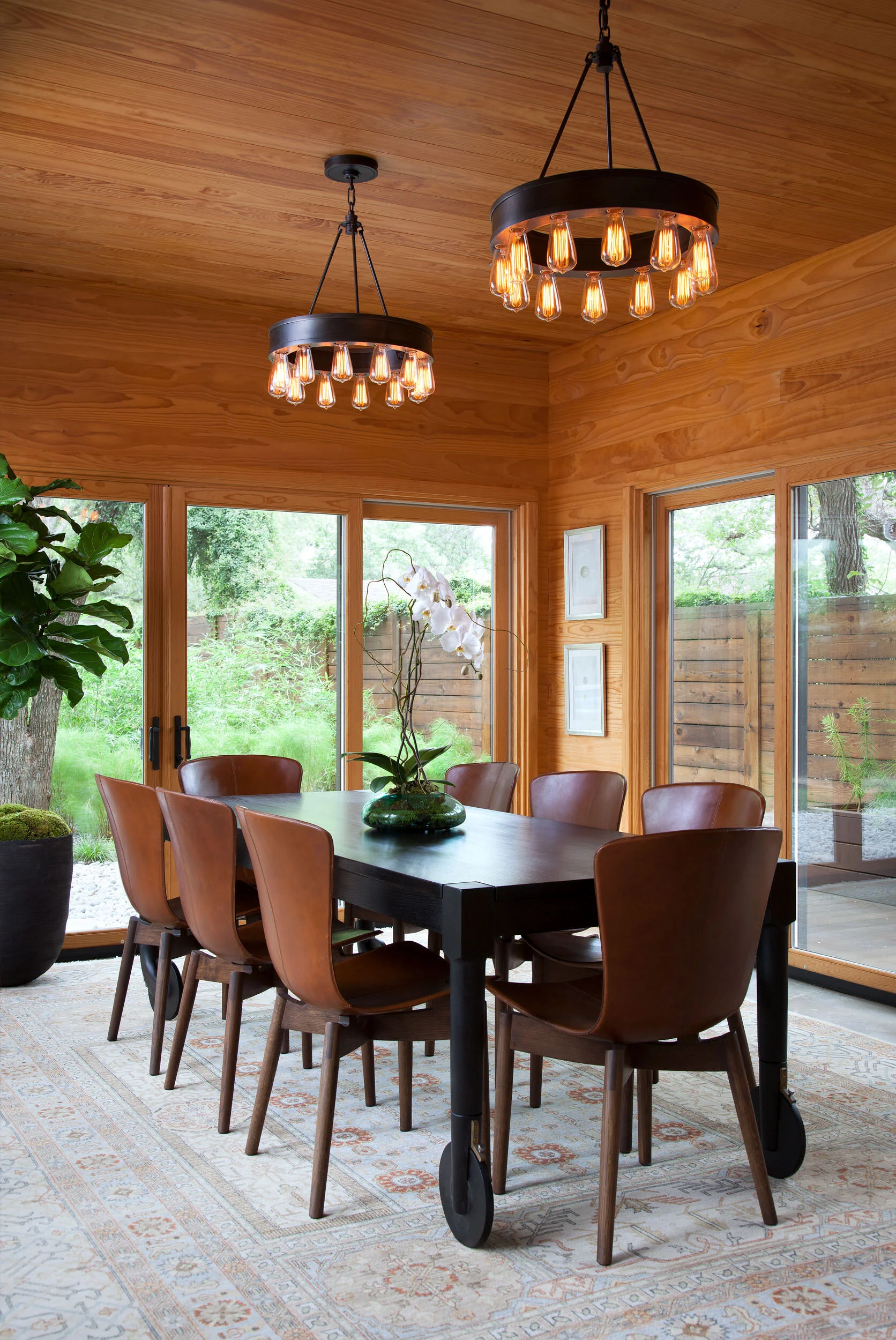  Dining room with wood-paneled ceiling and walls and custom dining table on wheels at Zilker Contemporary, designed by Mark Cravotta. 