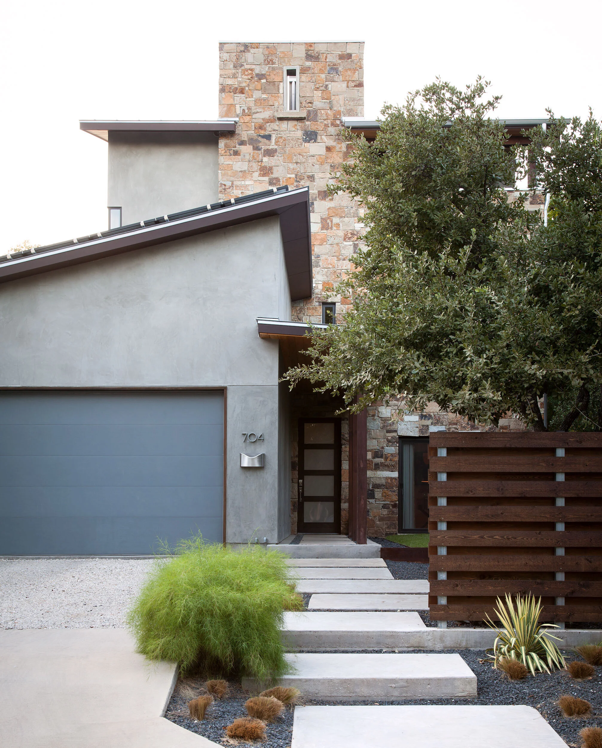  Exterior view of concrete plaster and stone at the Zilker Contemporary South Austin home by Cravotta Interiors. 