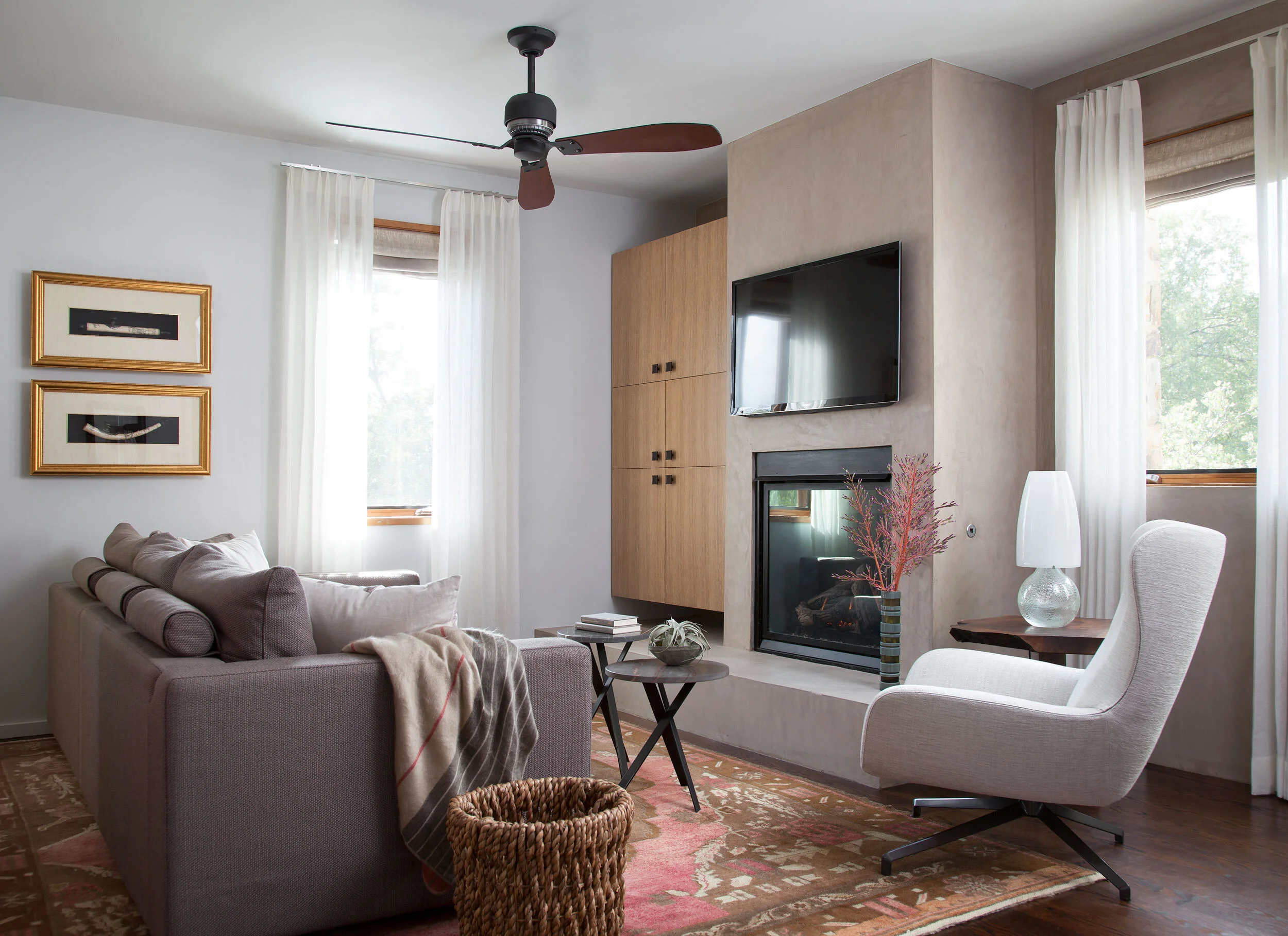  TV room with concrete fireplace, antique rug, and Minotti Jensen chair at Zilker Contemporary by Cravotta Interiors. 