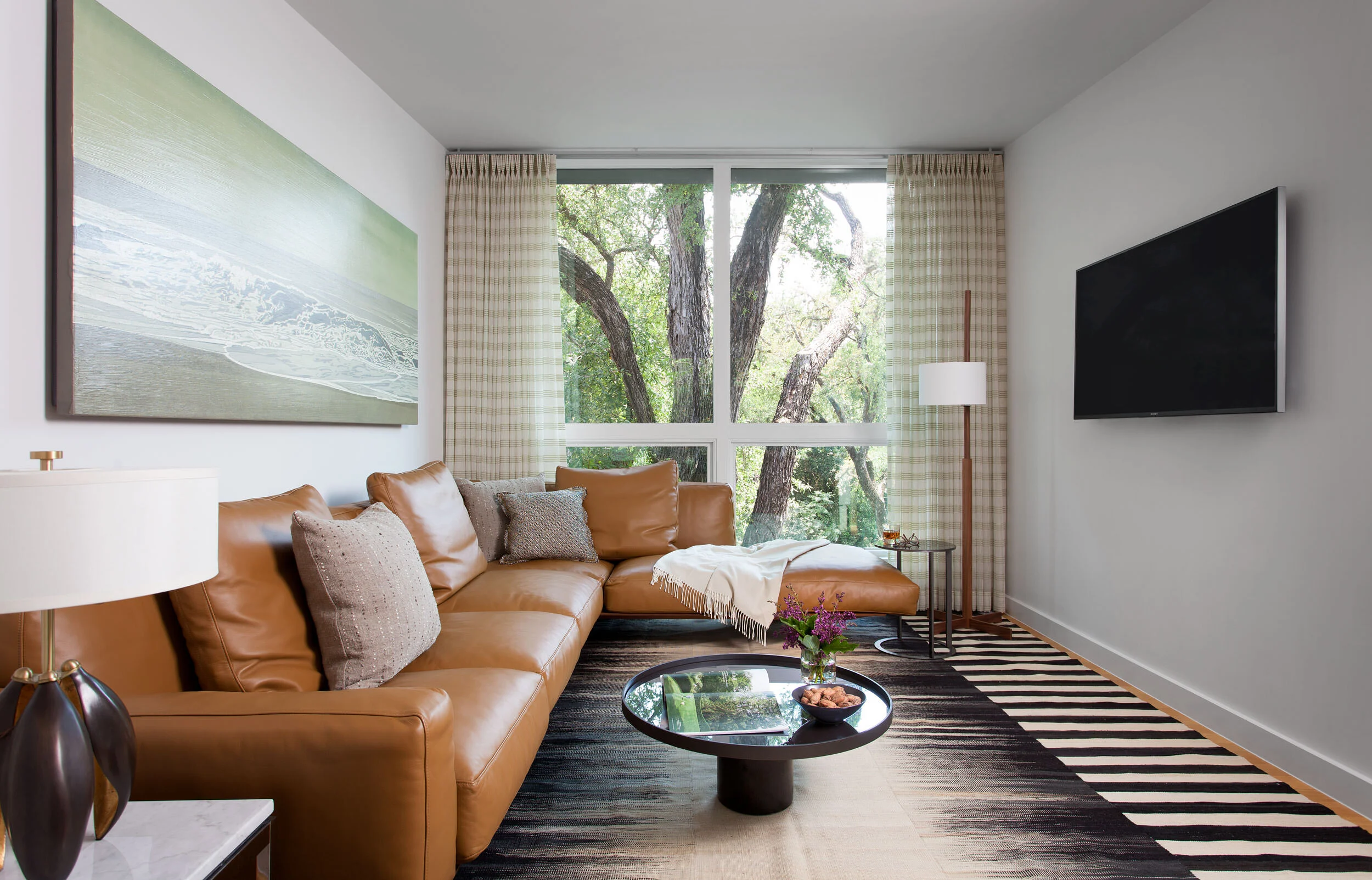  TV room with leather sectional and sheer drapes in the Clarksville home, designed by Mark Cravotta. 