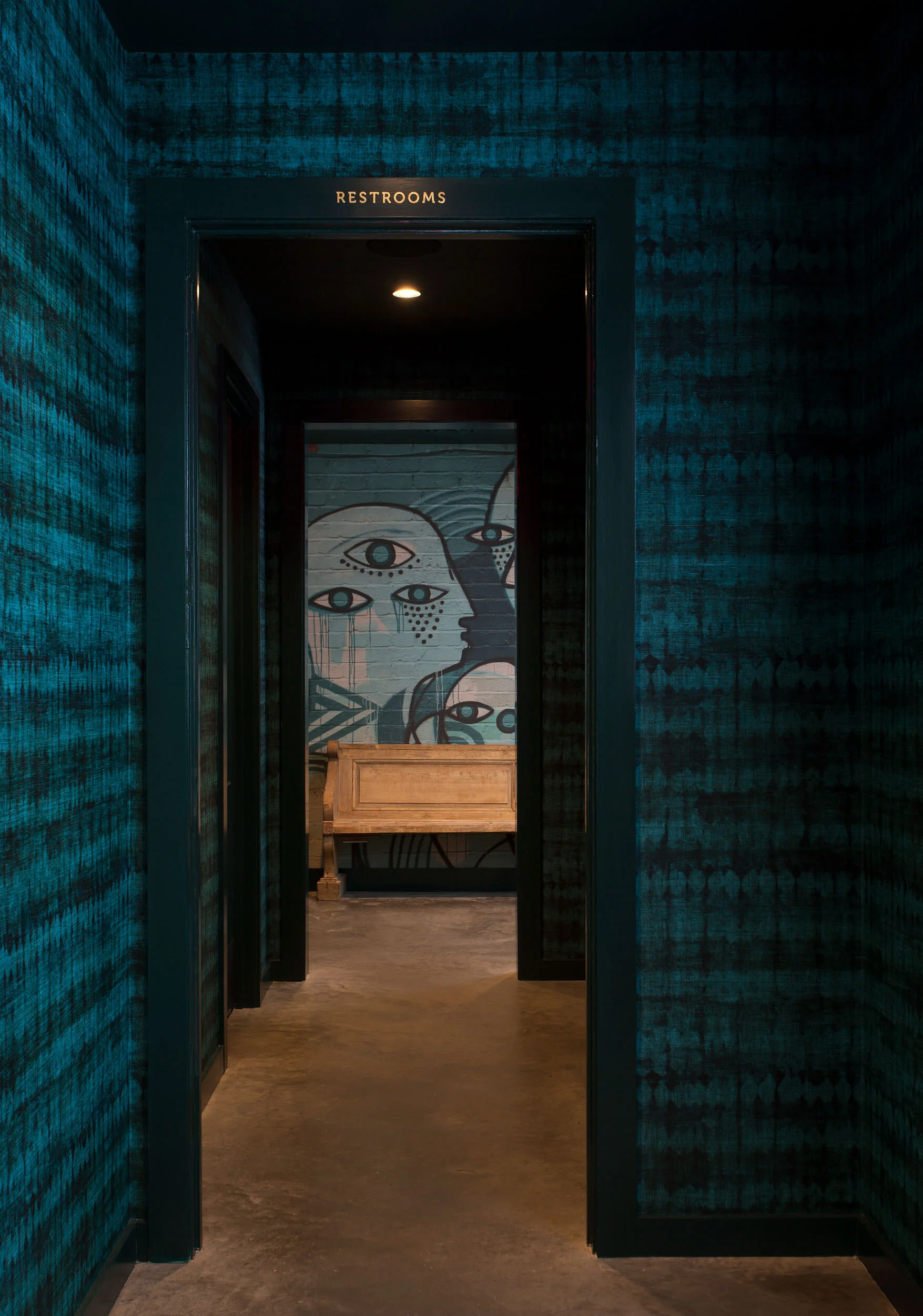  Restroom hallway with blue walls, custom wallpaper, and antique bench at Oseyo, designed by Mark Cravotta. 