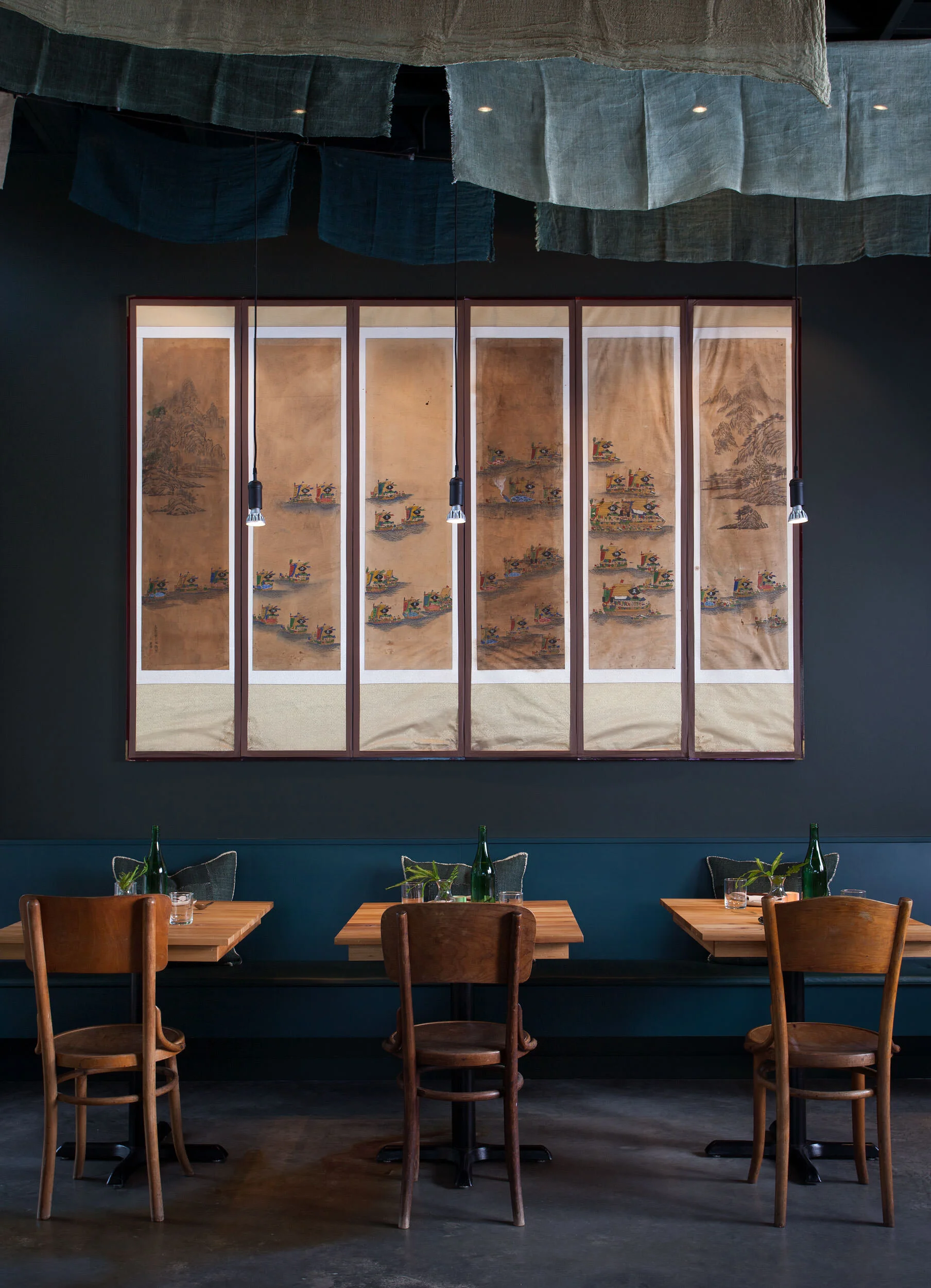  Banquette seating with blue walls and antique linen scrim suspended from the ceiling at Oseyo by Cravotta Interiors. 