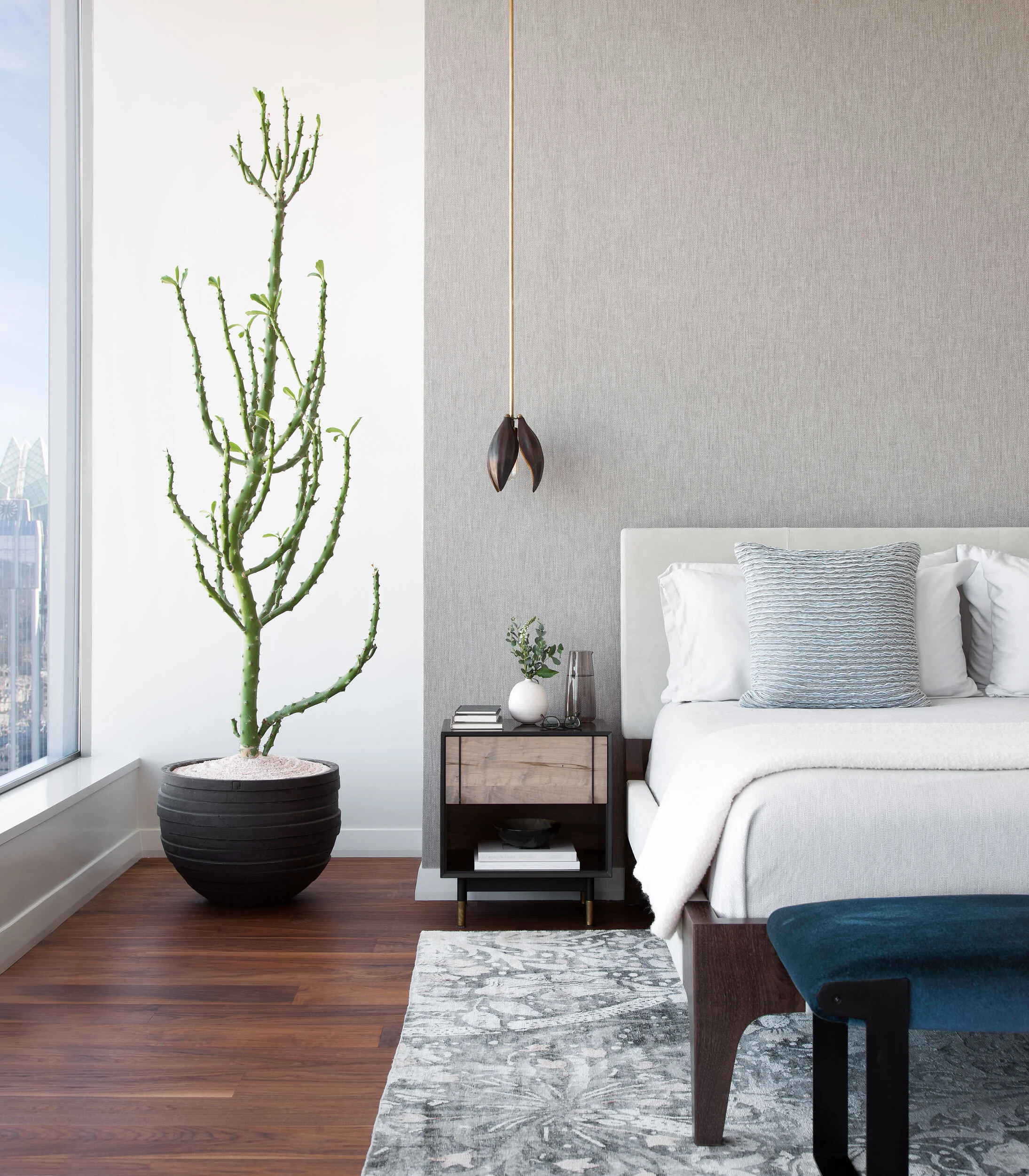  Close view of Holly Hunt bed with fabric wallcovering and specimen cactus in the W Penthouse primary bedroom by Cravotta Interiors. 
