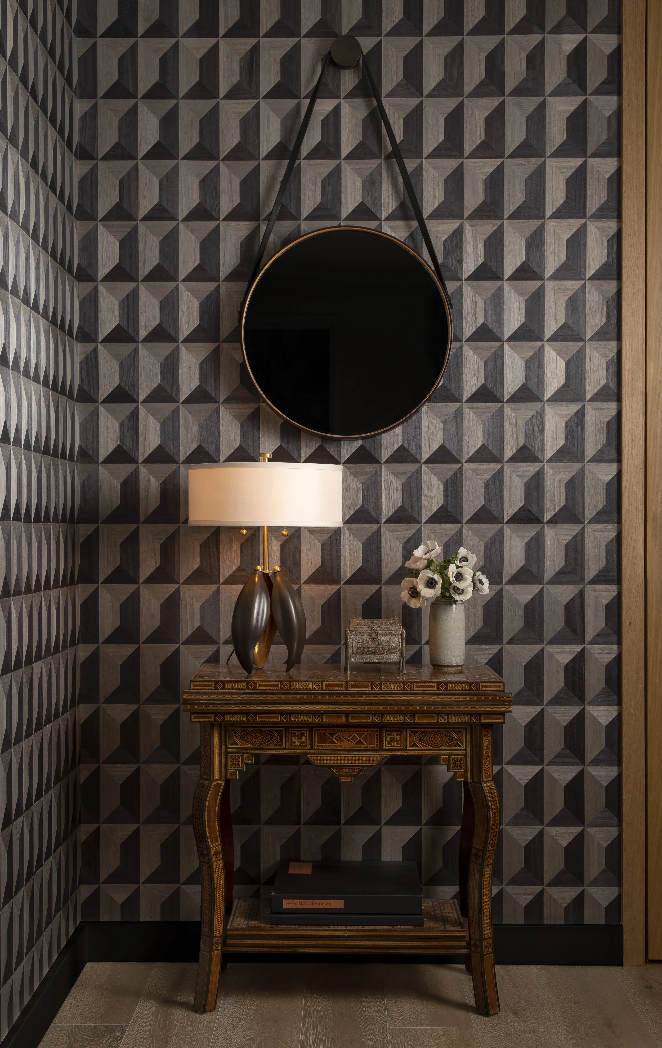  Entry with wood mosaic wallcovering, moody palette, and antique table at the Proper Residence, designed by Mark Cravotta. 