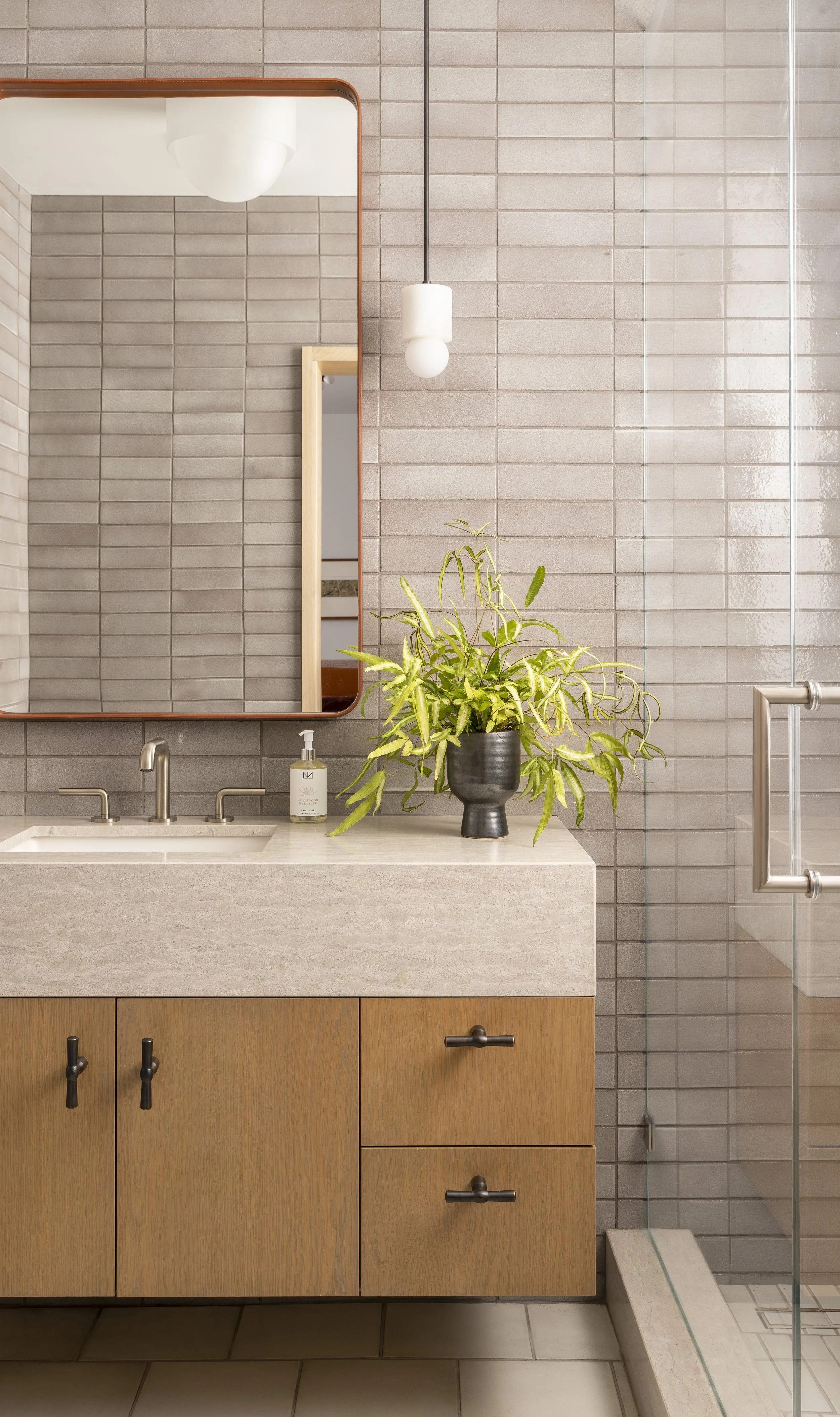  Guest bathroom with custom vanity, handmade tile, and leather-framed mirror at Boulevard Oaks by Cravotta Interiors. 