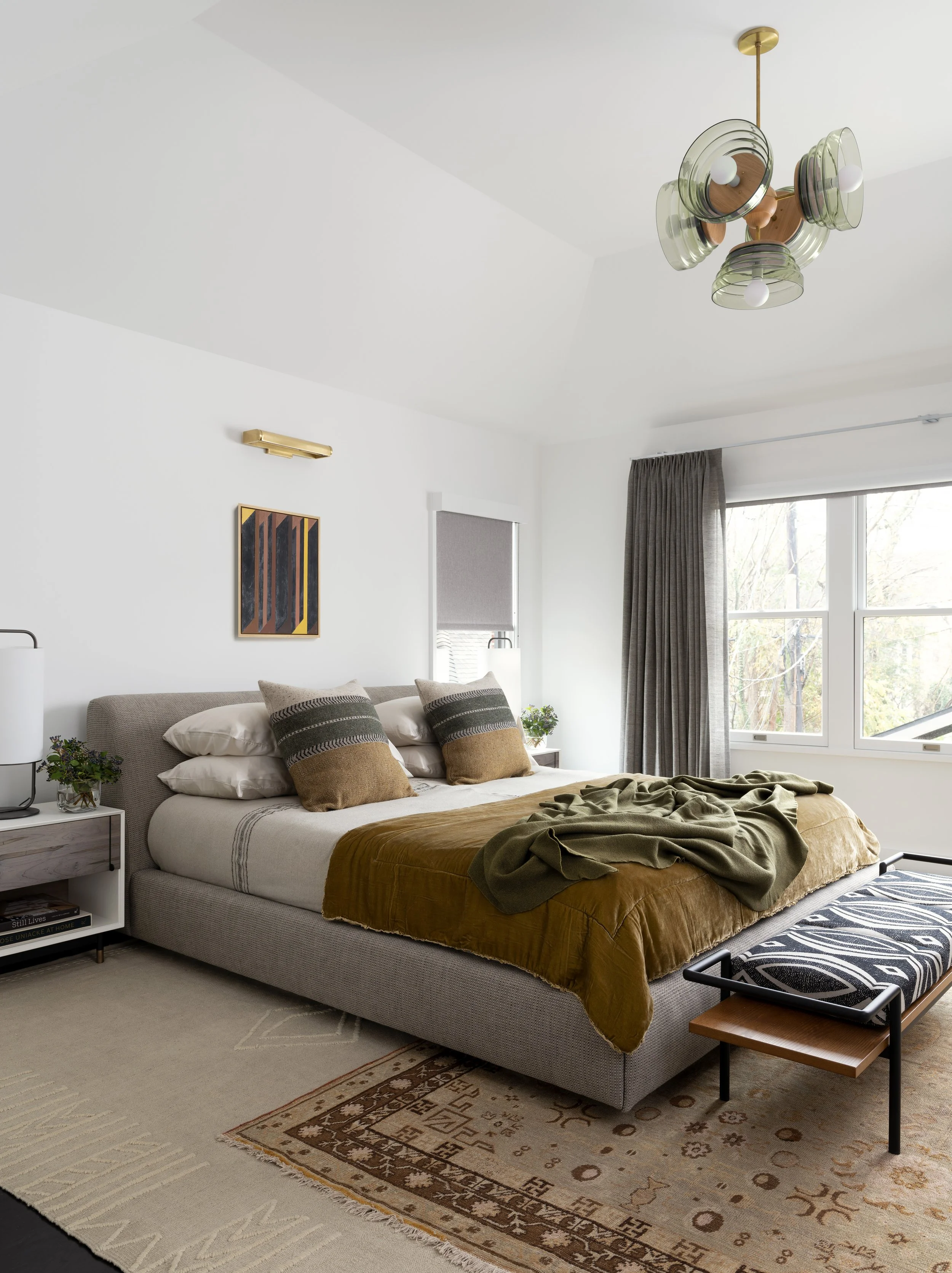 Primary bedroom with layered vintage rugs and sheer drapes in the Boulevard Oaks Houston remodel, designed by Mark Cravotta. 