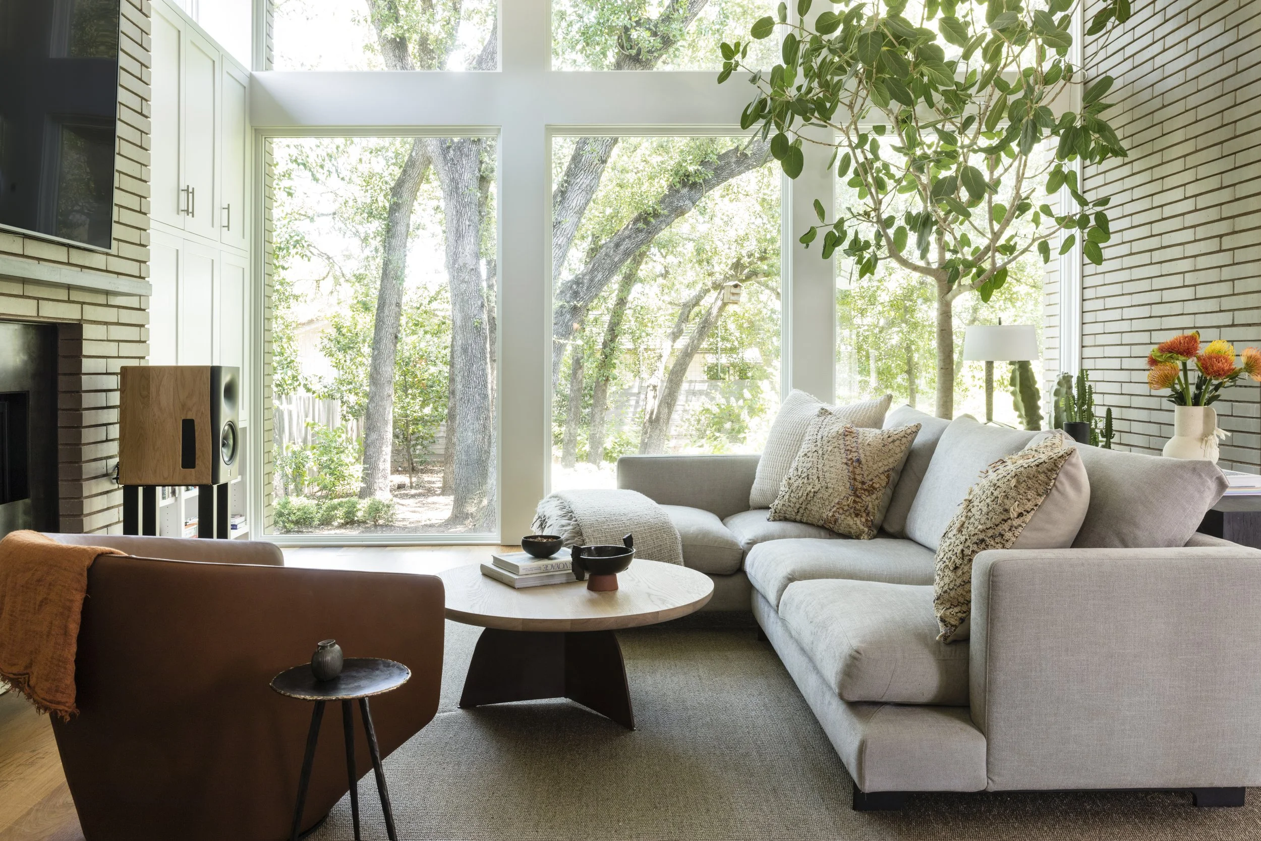  Living room with brick wall, indoor tree, and audiophile speakers at Rabb Road, designed by Mark Cravotta. 