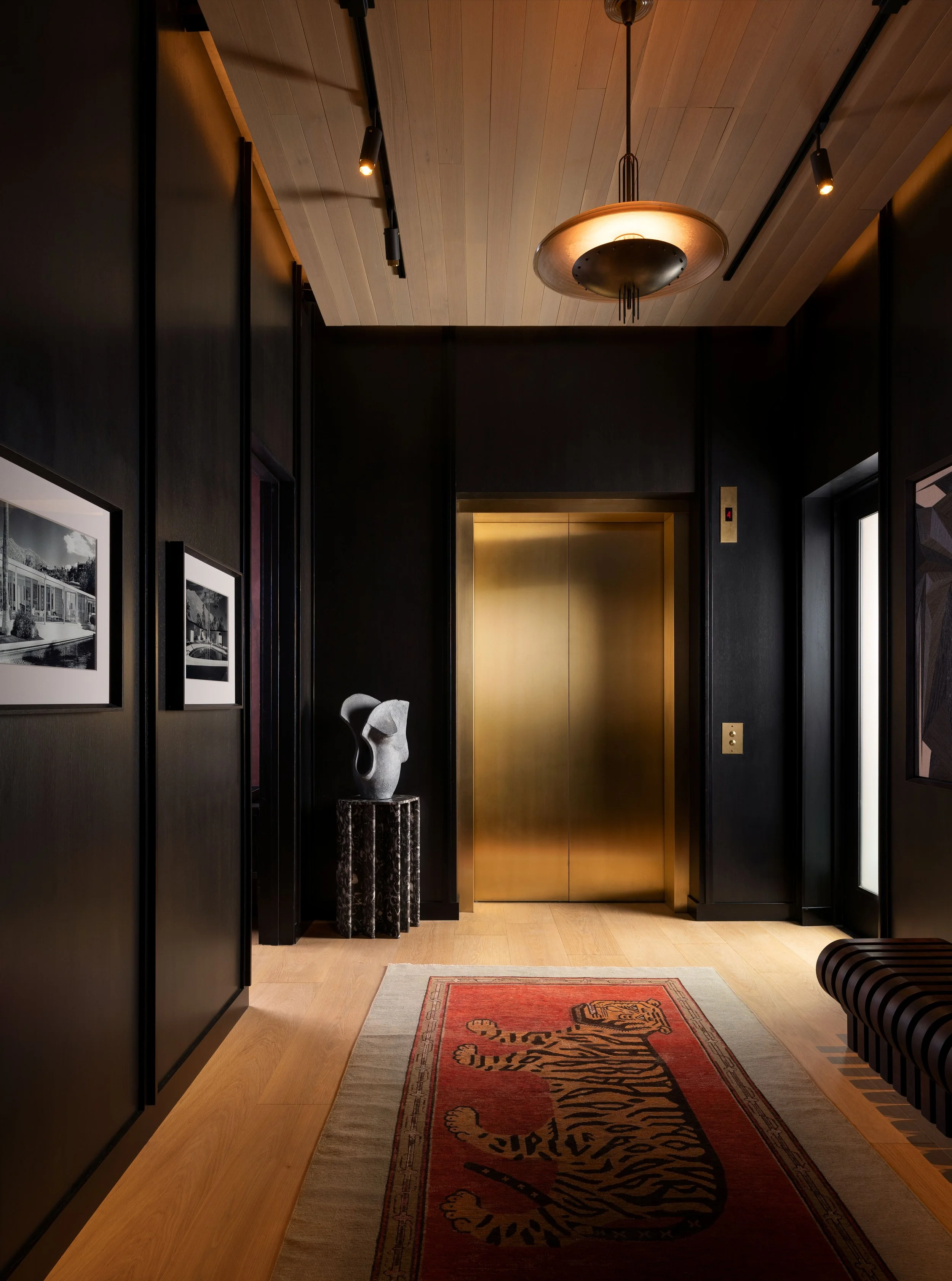 Wide view of the St. Cecilia foyer with Apparatus Studio chandelier, wood ceiling, and antique rug, designed by Mark Cravotta. 