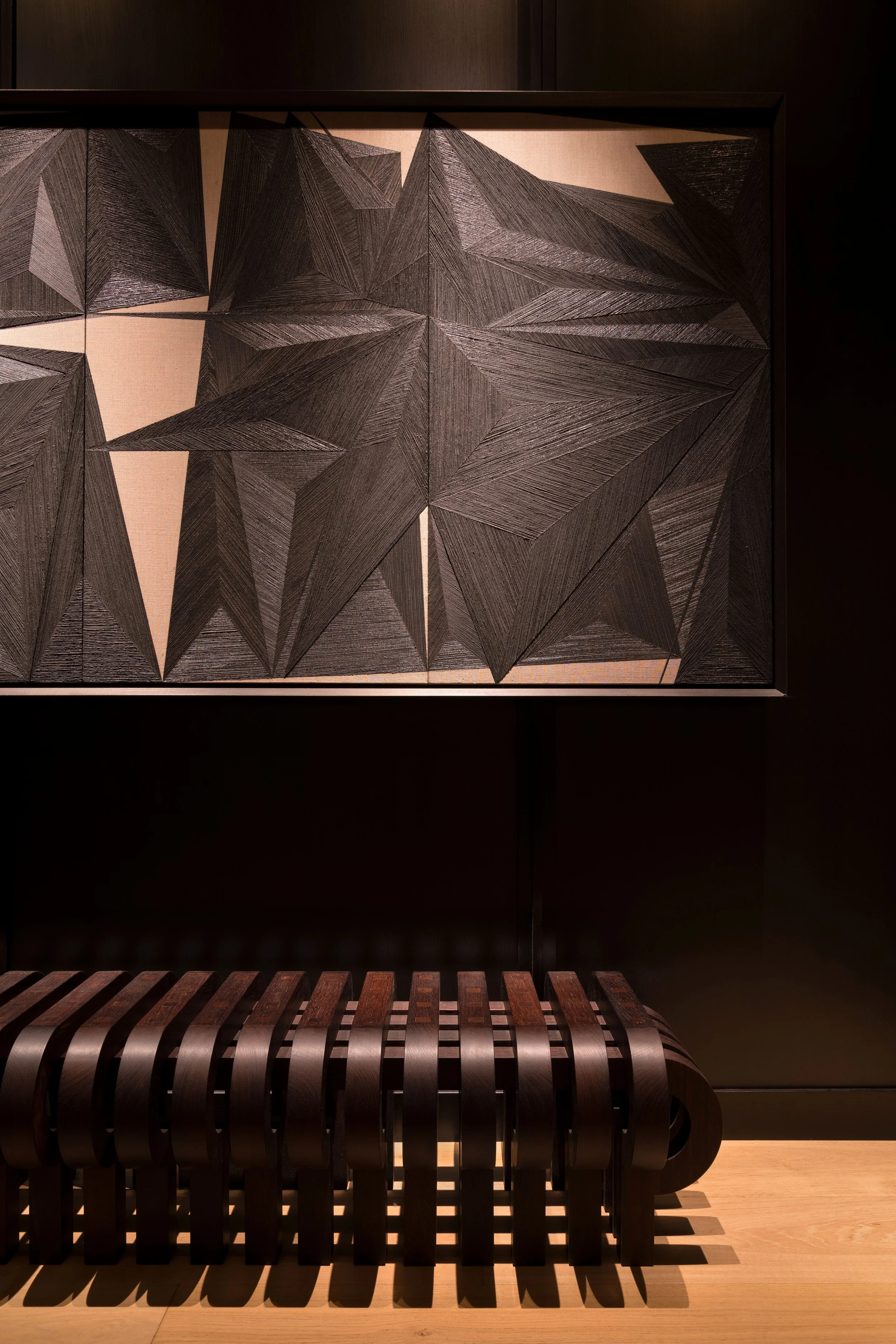  Sculptural wood bench against dark paneled walls in the St. Cecilia foyer, designed by Mark Cravotta. 