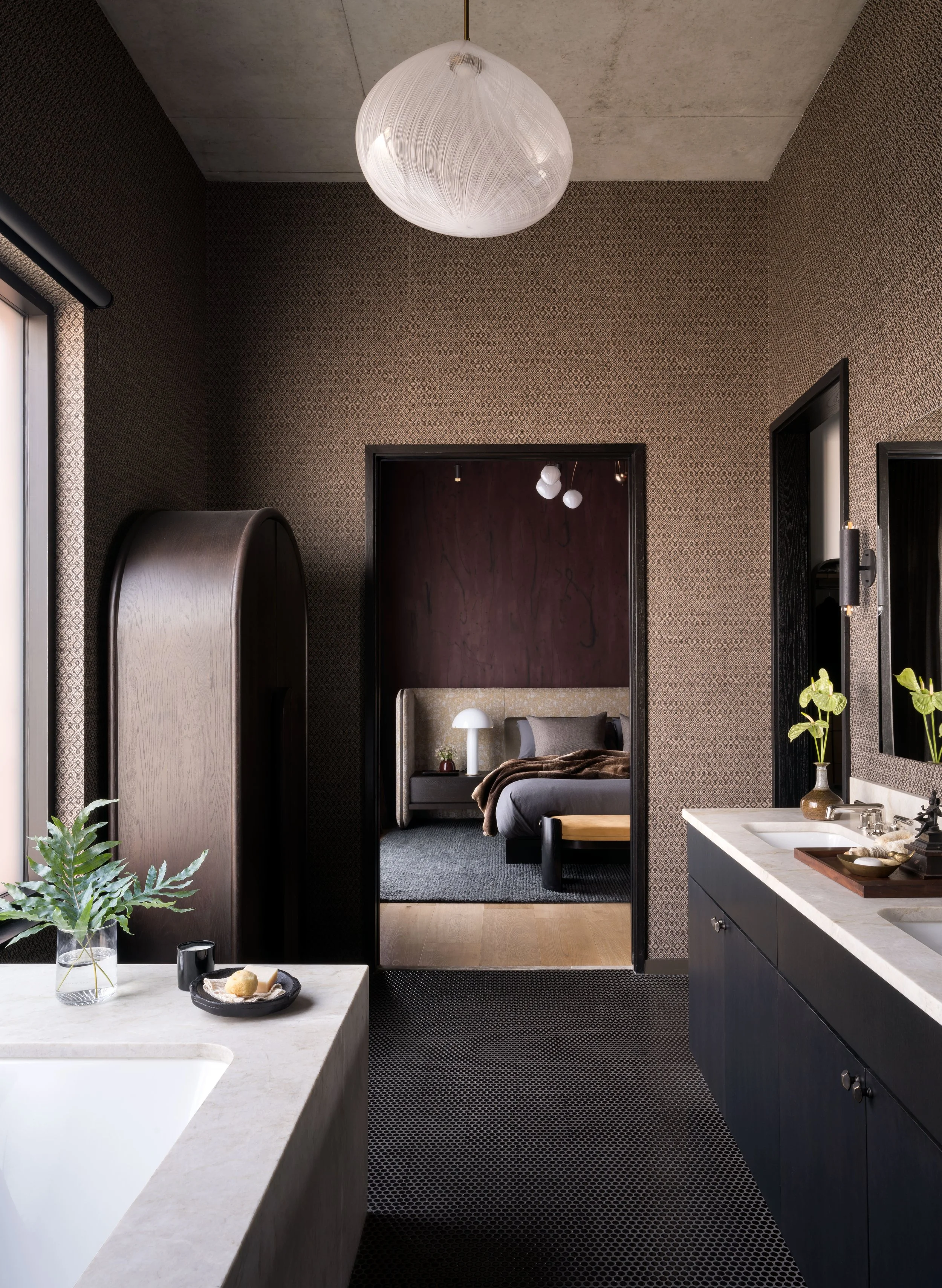  Moody primary bathroom with JMW Studio light fixture and dark natural wallcovering at St. Cecilia by Cravotta Interiors. 